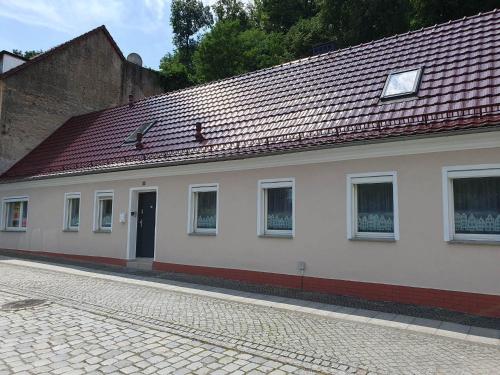 ein weißes Gebäude mit rotem Dach auf einer Straße in der Unterkunft Under the Hill 1 in Bad Muskau