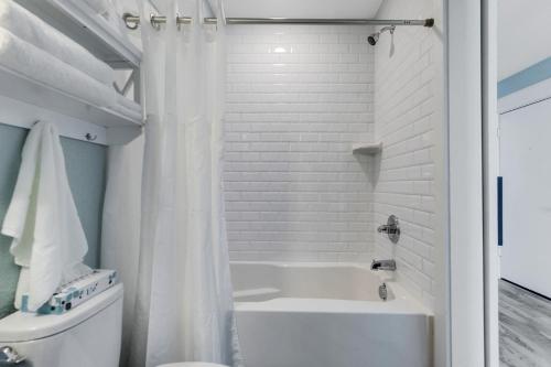 a white bathroom with a tub and a toilet at JY422 - John Yancey Oceanfront Inn Penthouse Suite in Kill Devil Hills