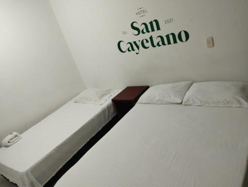 two beds in a room with a sign on the wall at Hotel San Cayetano in Ocaña