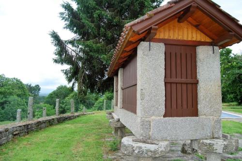 un pequeño edificio en una pared de piedra en un cementerio en Casa rural con piscina 