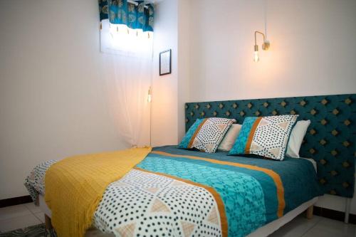 - une chambre avec un lit doté de couvertures et d'oreillers colorés dans l'établissement Maison de village rénovée à 10 minutes des plages, à Saint-Laurent-de-la-Salanque