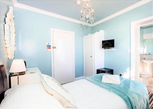 a blue bedroom with a bed and a chandelier at East Beach Hotel in Eastbourne