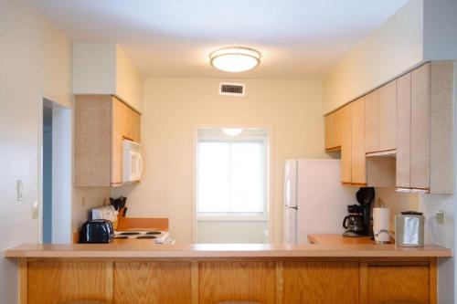 a kitchen with wooden cabinets and a white refrigerator at SR-T2 - Sea Ranch Resort - Prime Oceanfront condo Oceanviews Indoor Pool Restaurant in Kill Devil Hills