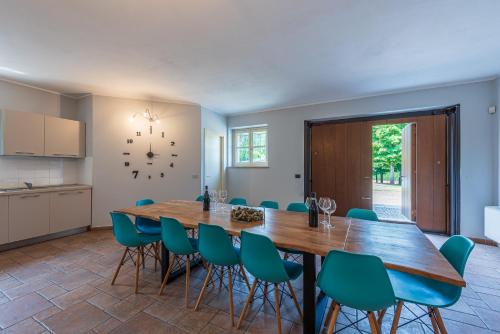 une salle à manger avec une table en bois et des chaises bleues dans l'établissement Villa Cornelia , entire Villa with private pool, à Corneliano d'Alba