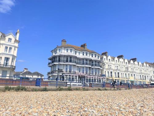 a large white building on the beach next to at East Beach Hotel in Eastbourne