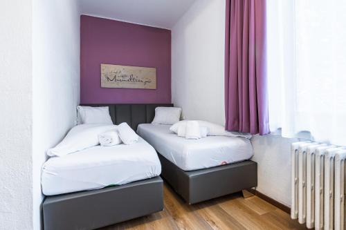 two beds in a room with a purple wall at Lake and Cityhotel Edelweiss - self Check in in Zell am See