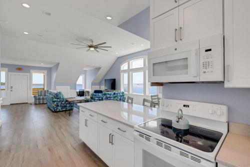 a kitchen with white cabinets and a living room at Sunrises to Sunsets in Nags Head