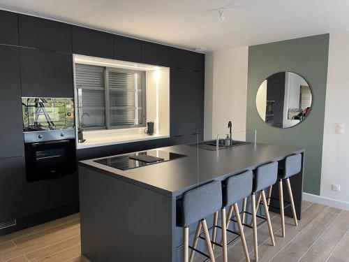 a kitchen with black cabinets and a counter with bar stools at Gîte Luna ; villa 6 personnes avec jaccuzi in Chaumont-sur-Loire