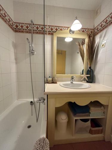 een badkamer met een wastafel, een bad en een spiegel bij Appartement vue mer Golfe de Saint-Tropez in Les Issambres