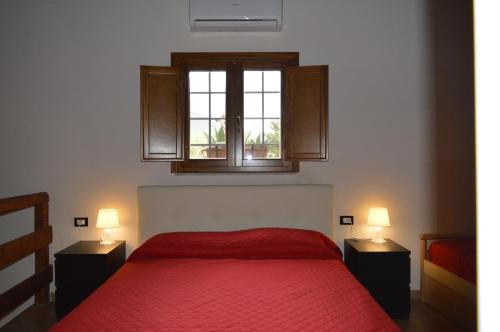 a bedroom with a red bed and a window at Villa in Antico Baglio in Castellammare del Golfo