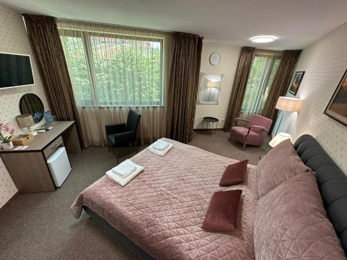 ein Hotelzimmer mit einem großen Bett und einem Schreibtisch in der Unterkunft Хотел АВРОРА in Chaskowo