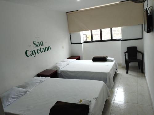 a room with three beds and a chair in it at Hotel San Cayetano in Ocaña