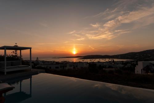 a sunset over a city with a swimming pool at Orasea Villa with private pool in Parikia