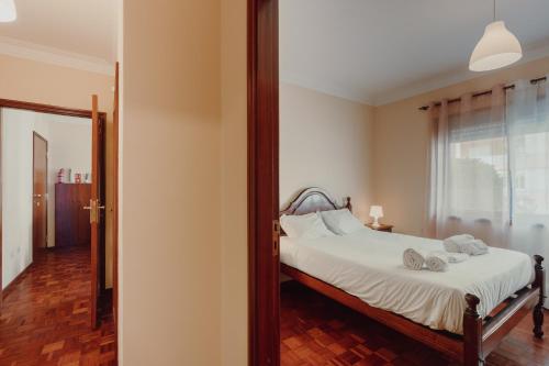 - une chambre avec un lit doté de draps blancs et d'un miroir dans l'établissement Rising Sun Apartment, à Leça da Palmeira