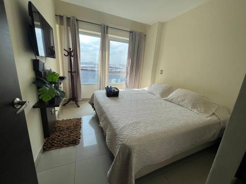 um quarto com uma cama e uma grande janela em Coffee Suite, wifi, Parqueo, gym & piscina! em Guayaquil