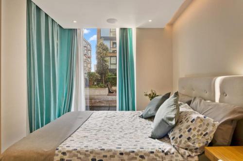 倫敦的住宿－Canal Side Luxury 1 Bed Chelsea，一间卧室配有一张带绿色窗帘的床和窗户。