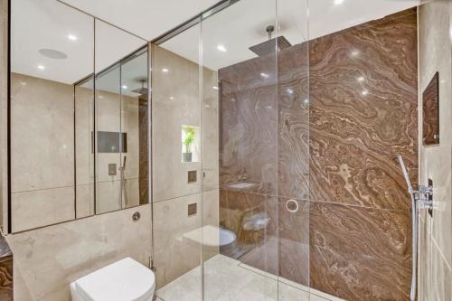 uma casa de banho com um WC e uma cabina de duche em vidro. em Canal Side Luxury 1 Bed Chelsea em Londres