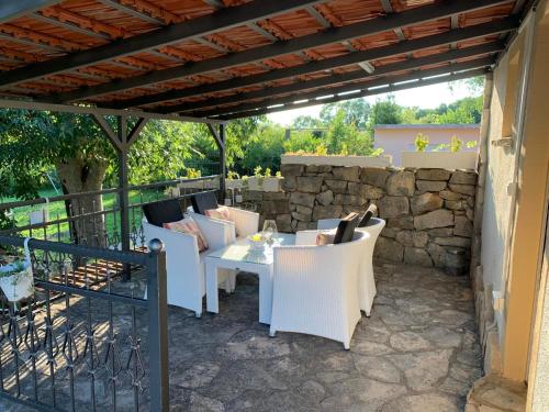 a patio with white chairs and a table and a stone wall at Kuca za iznajmljivanje ANDRIJA in Ljubuški