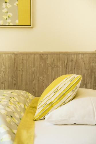 a bed with yellow and white pillows on it at Hotel & Restaurant Sonne in Kirchzarten