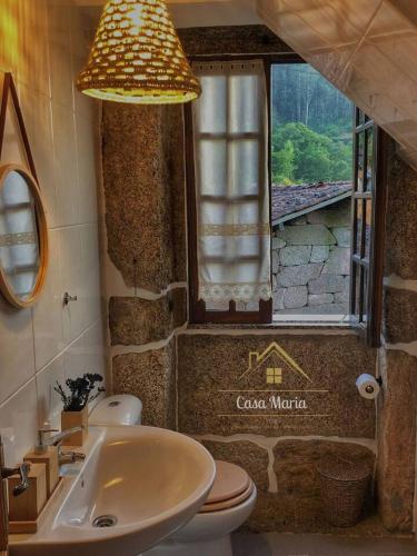 a bathroom with a sink and a toilet and a window at Casa Maria in Terras de Bouro