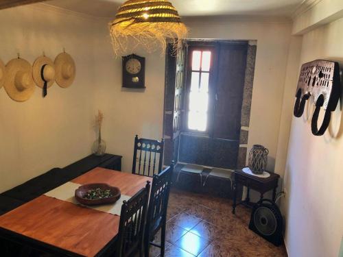 a dining room with a wooden table and a clock at Casa Maria in Terras de Bouro