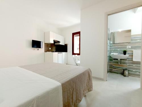 a white bedroom with a bed and a sink at Monolocali Cavour - Affitti Brevi Italia in Ulassai