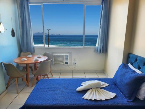 a bedroom with a blue bed with a table and a window at Studio com a Melhor Vista do Rio TC602 in Rio de Janeiro