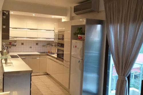 eine Küche mit weißen Schränken und einem Kühlschrank aus Edelstahl in der Unterkunft A-CLASS APARTMENT,near the sea & Patras University in Patras