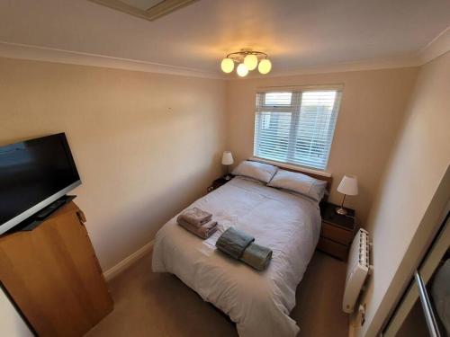 een slaapkamer met een bed en een flatscreen-tv bij Bungalow a few minutes from the sea. in The Mumbles