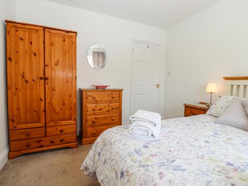a bedroom with a bed with a wooden dresser and a cabinet at Bay Tor in Dover