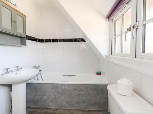 a white bathroom with a sink and a bath tub at Magnolia Cottage Osmington in Osmington