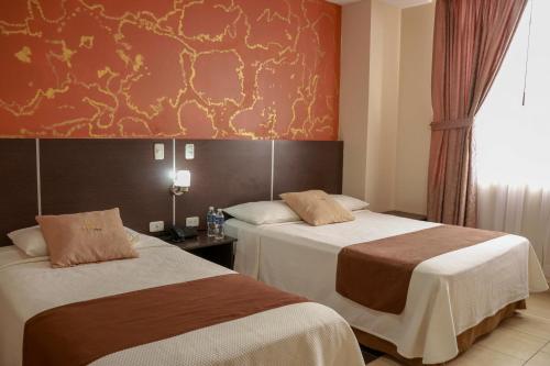 a hotel room with two beds and a red wall at Hotel Golden Vista in Santo Domingo de los Colorados