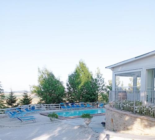 uma piscina num resort com cadeiras azuis em B&B Profumo Di Gelsomino em Mombaroccio