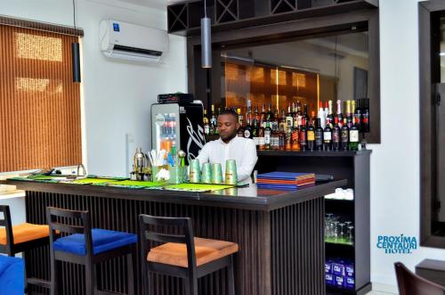 un hombre parado detrás de un bar en un restaurante en Proxima Centauri Hotel, en Port Harcourt