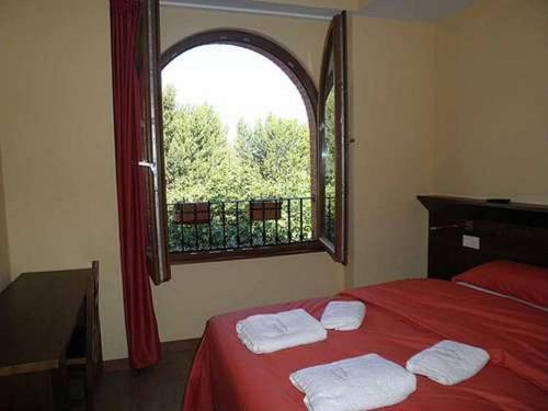 1 dormitorio con cama roja y ventana en Cueva Restaurante Itariegos en Villagallegos