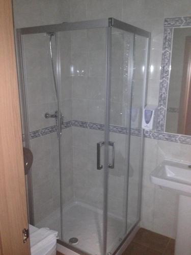 a shower with a glass door next to a sink at Cueva Restaurante Itariegos in Villagallegos