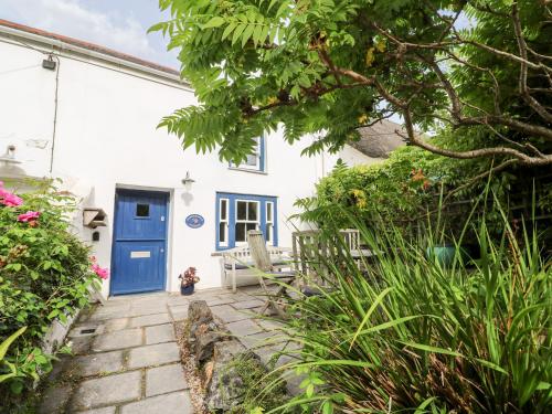 a cottage with a blue door and a patio at Honeysuckle Cottage in St. Agnes
