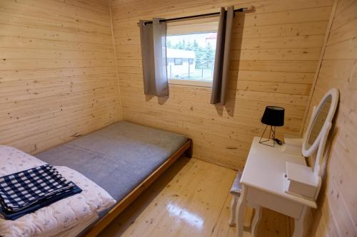 um pequeno quarto com uma cama e uma secretária em Letnie Chatki Nowe Guty em Nowe Guty