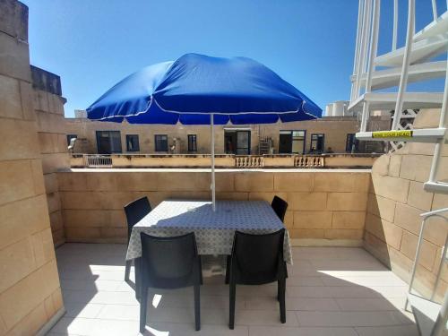 a table with a blue umbrella on a patio at East Breeze Penthouse in Mġarr