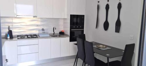 a kitchen with white cabinets and a table with black utensils at Cazinos Apartamento in Praia