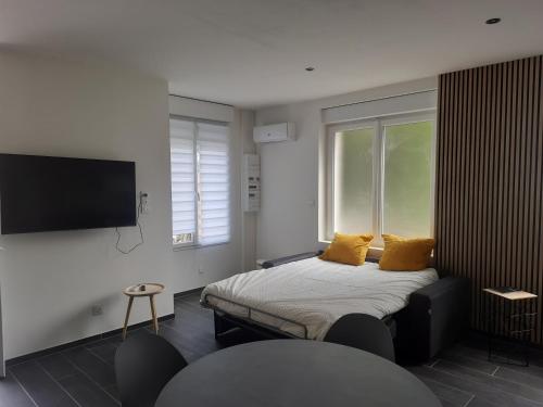 1 dormitorio con 1 cama con almohadas amarillas y TV en La clef des champs gite CLOTILDE, en Brouckerque