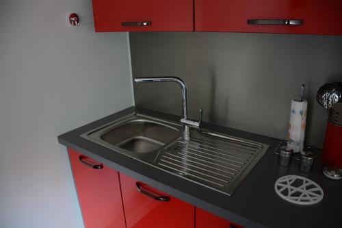 un lavandino con rubinetto e armadi rossi di SWEETHOME DIJON - ALBERT 1er a Digione