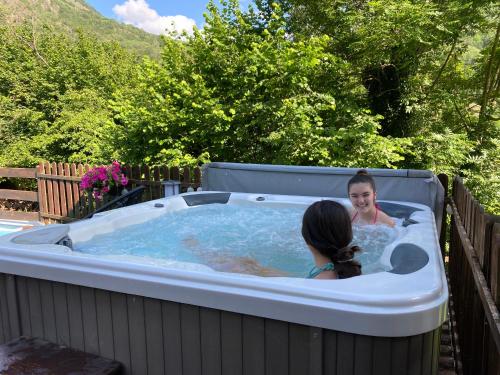 two girls in a hot tub in a backyard at Apartaments Alta Muntanya in Barruera