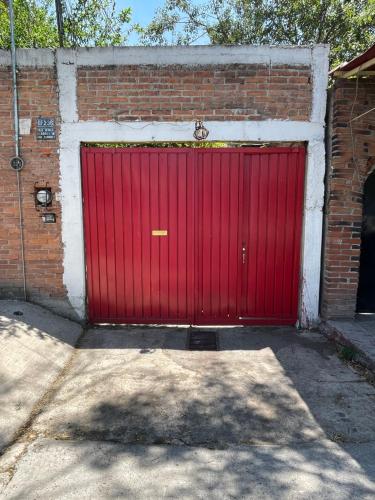 een rode garagedeur op een bakstenen gebouw bij Casa H236 in Mexico-Stad