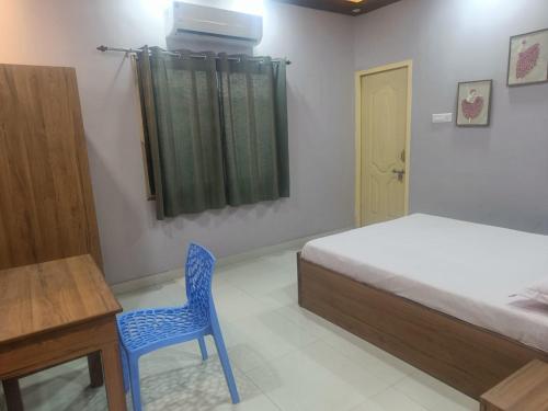 a bedroom with a bed and a desk and a blue chair at Rangili Baag in Varanasi