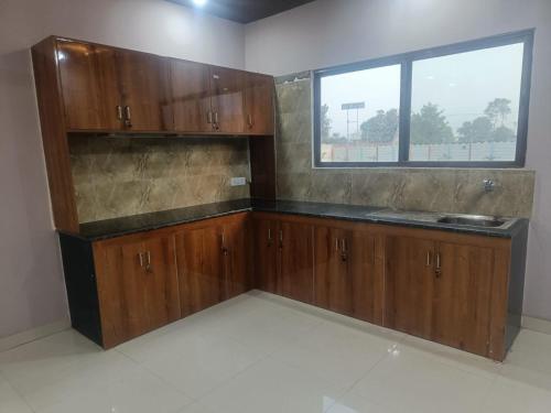 an empty kitchen with wooden cabinets and a window at Rangili Baag in Varanasi