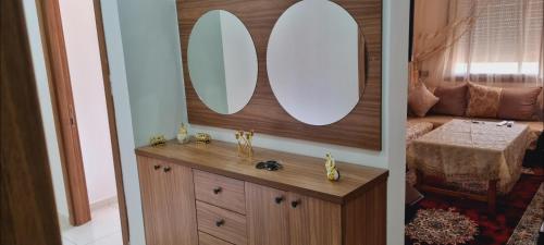 two pictures of a bathroom with a sink and mirrors at Résidence Toudert jiji in Agadir