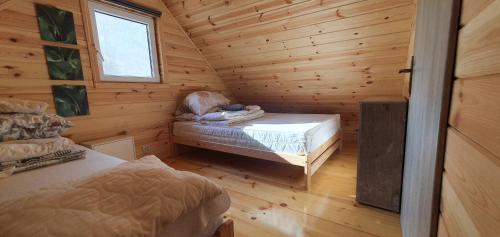 a small room with a bed in a log cabin at Leśne Zacisze in Łuka