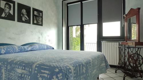 a bedroom with a bed with a blue comforter and windows at Residence Il Cantiere in Predore
