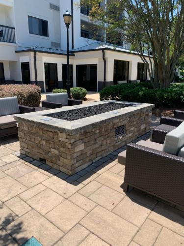 a stone fire pit in a courtyard with benches at Courtyard by Marriott Charlotte Ballantyne in Charlotte